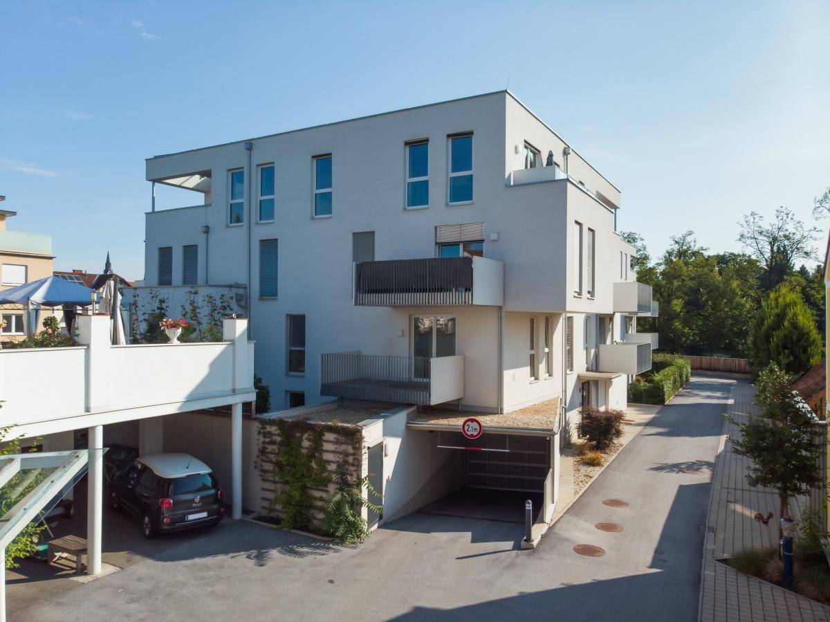 Modernes Mehrfamilienhaus mit Balkonen, Tiefgaragenzufahrt und gepflegter Außenanlage.