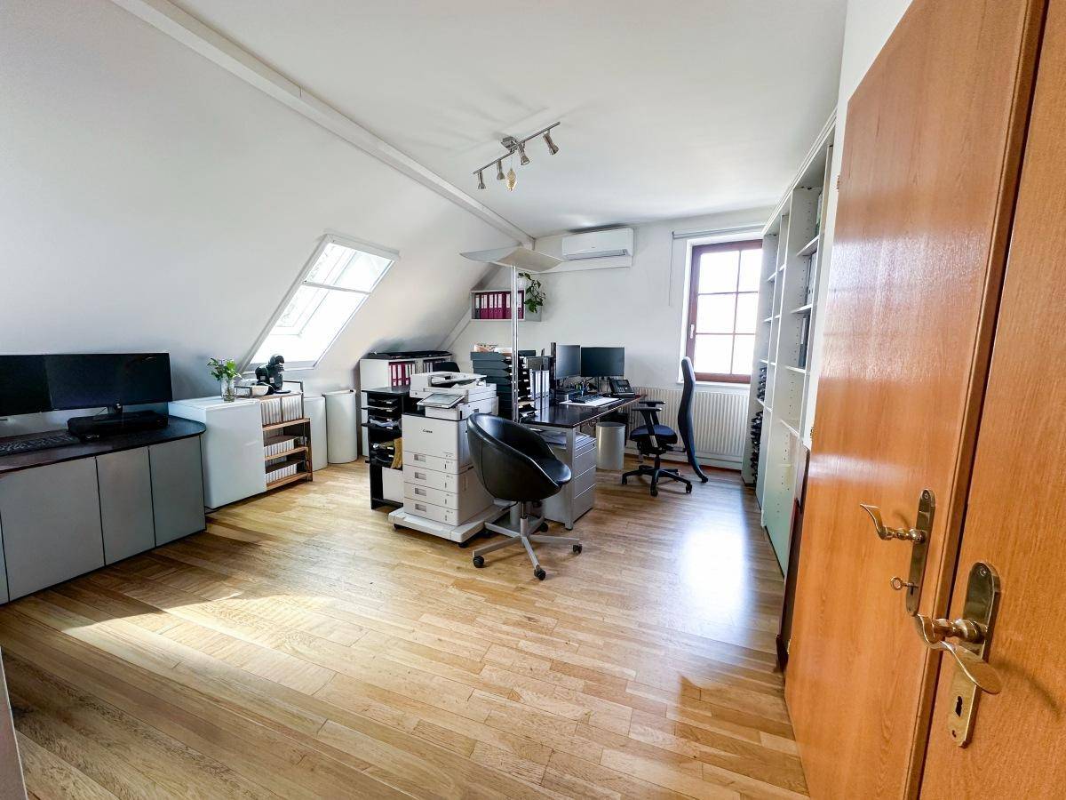 Geräumiges Büro im Dachgeschoss mit mehreren Arbeitsplätzen, Regalen, Dachfenster und Klimaanlage.