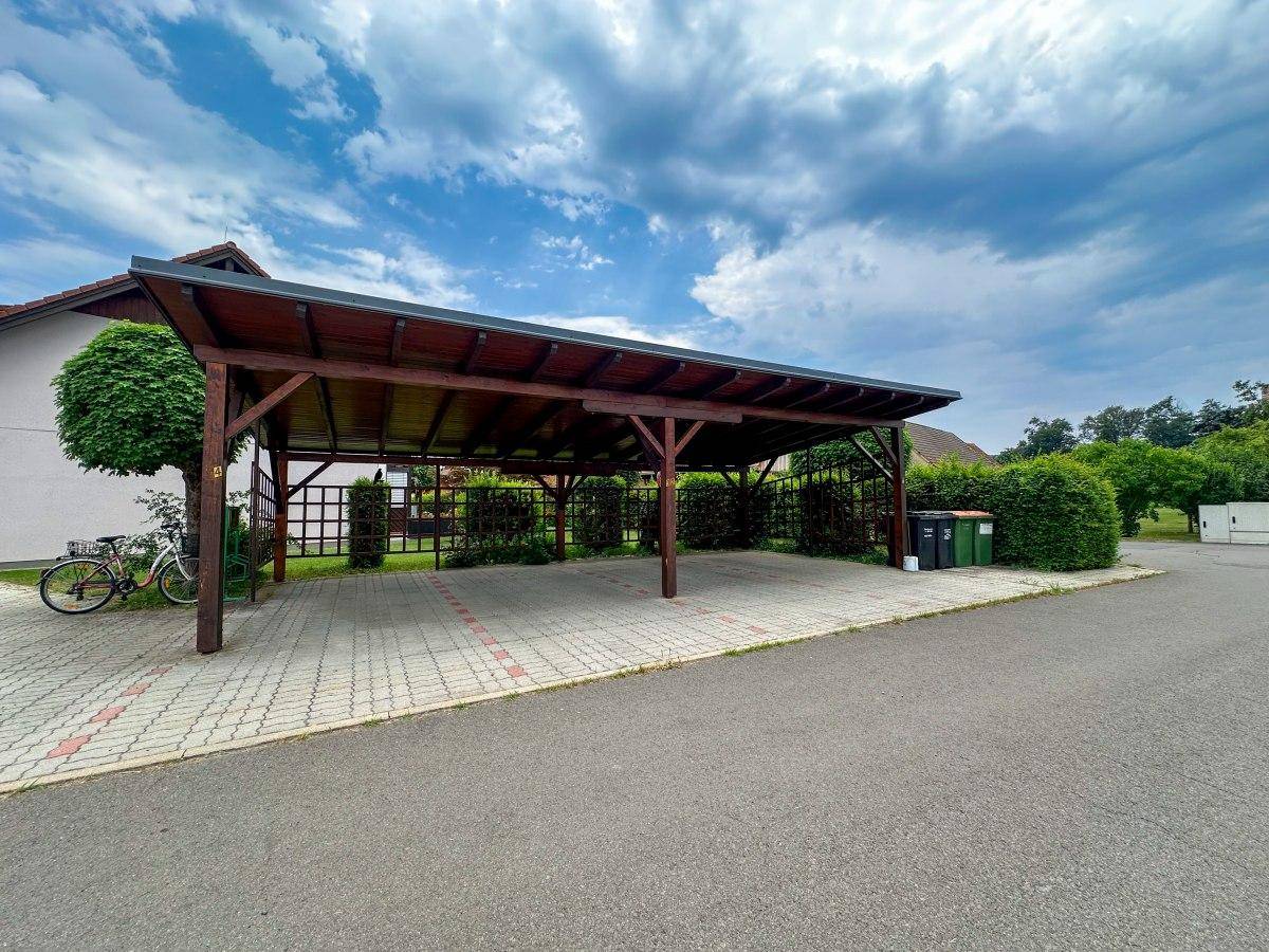 Überdachter Carport mit Holzkonstruktion bietet geschützten Parkraum für Fahrzeuge.