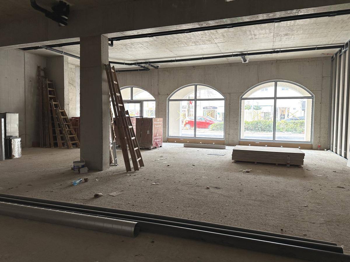 Großer Rohbau mit Betonwänden, Leitern und Bogenfenstern, die auf die Straße blicken.