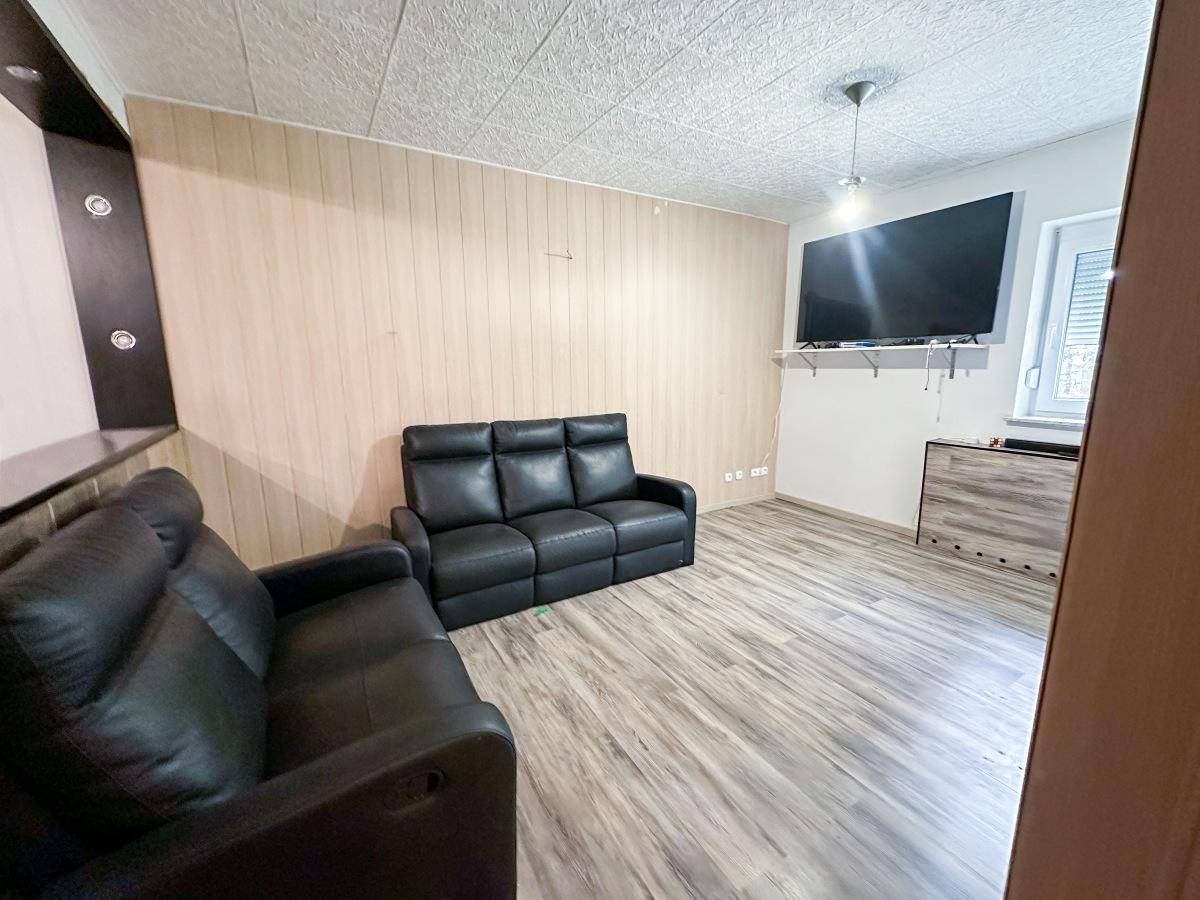 Wohnzimmer mit bequemen Ledersofas, Holzpaneelen und Fernseher an der Wand.