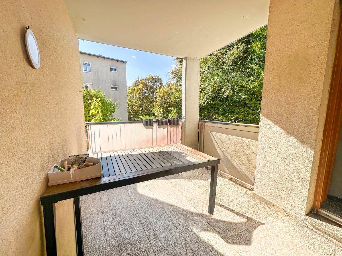 Sonniger Balkon mit Tisch und Blick auf die umliegende Natur.