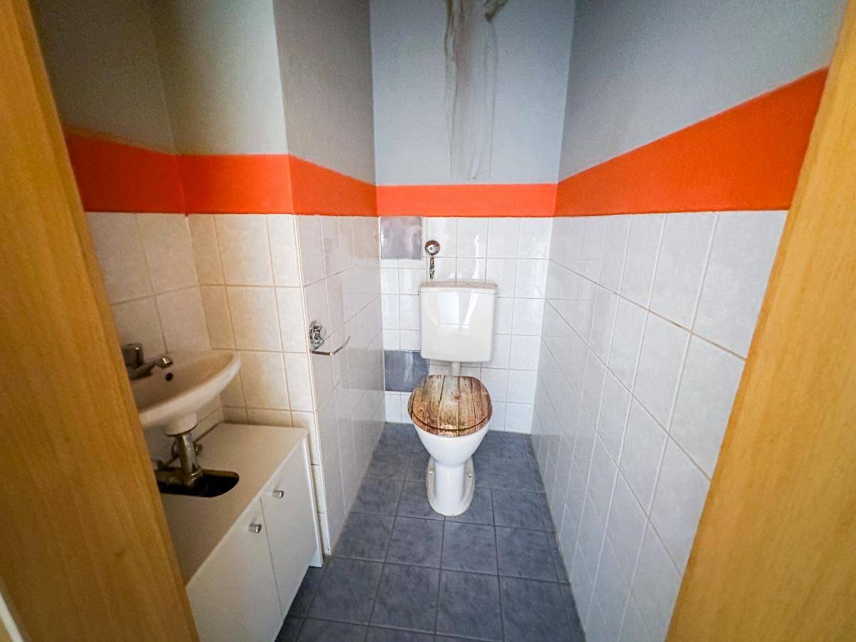 Kleines Gäste-WC mit weißen Wandfliesen, blauem Boden und einem Waschbecken.