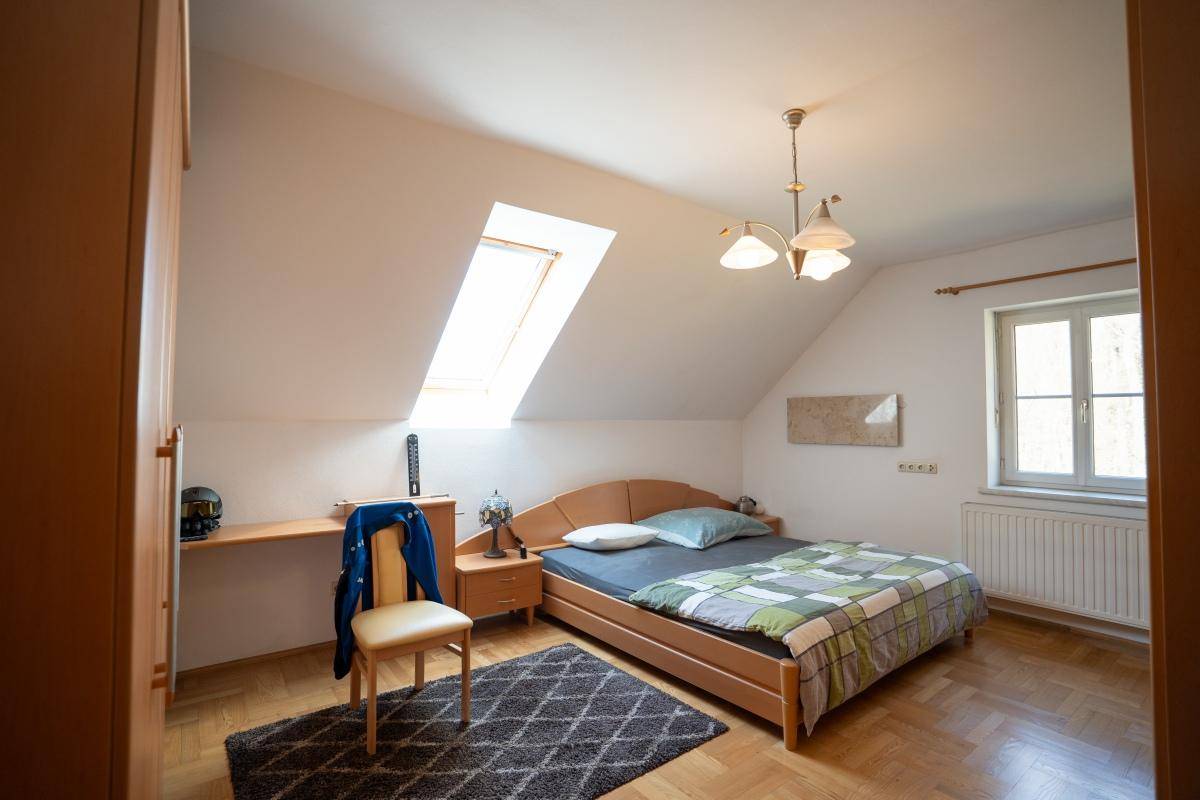 Gemütliches Schlafzimmer im Dachgeschoss mit Bett, Schreibtisch und Dachfenster.