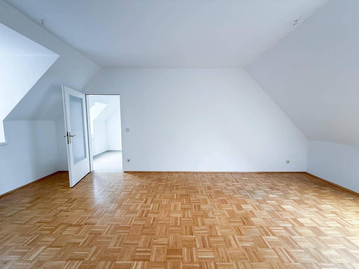 Geräumiges Zimmer mit Parkettboden, weißen Wänden und Dachschrägen, bereit zur individuellen Gestaltung.