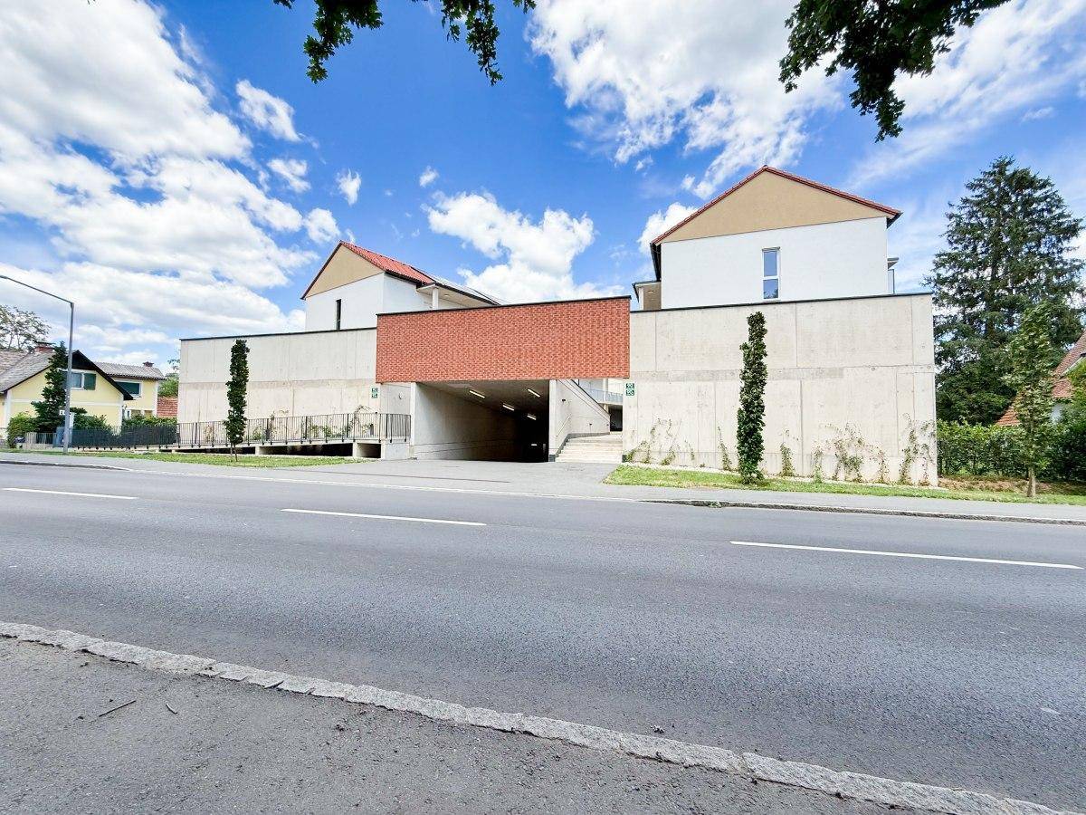 Straßenansicht des modernen Wohnkomplexes mit Zufahrt zur Tiefgarage und ansprechender Fassade.