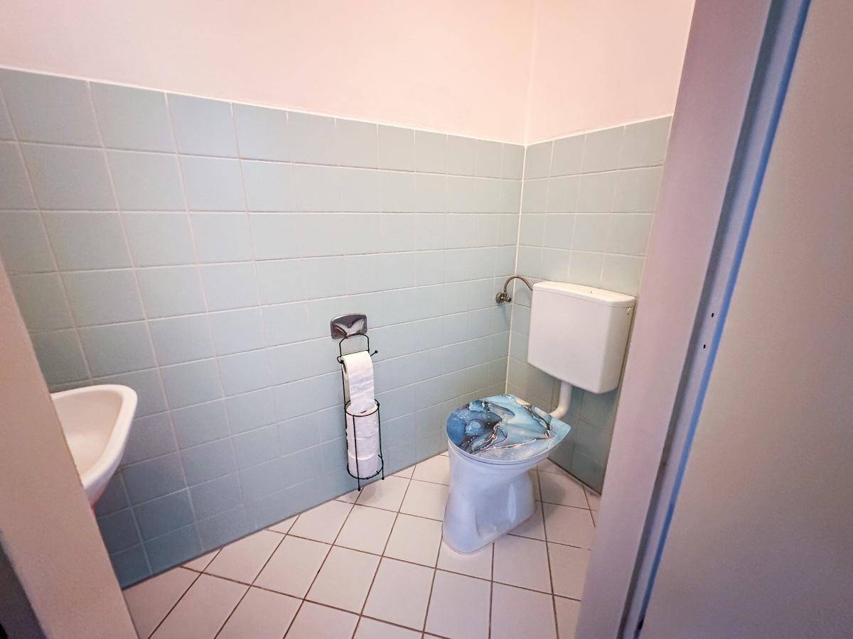 Kleines Gäste-WC mit hellblauen Fliesen, Toilette und Handwaschbecken.
