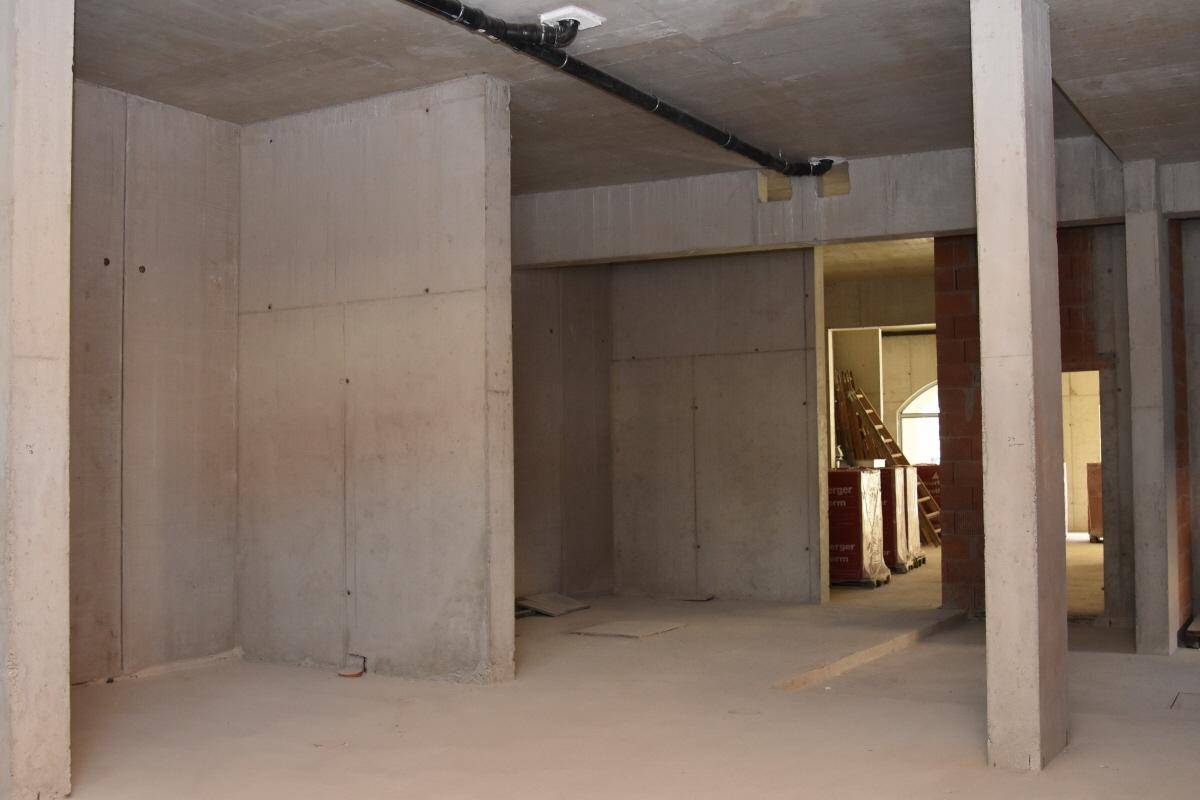 Großzügiger Rohbau mit Betonwänden, Säulen und sichtbaren Deckeninstallationen, der auf den Ausbau wartet.