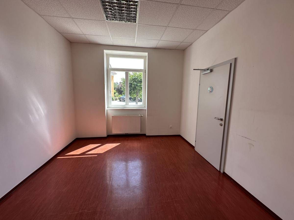 Heller Gewerberaum mit braunem Boden, weißen Wänden und einem großen Fenster.