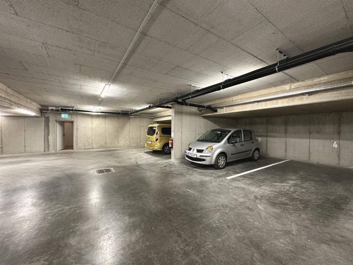 Tiefgarage mit mehreren Stellplätzen und Betonwänden, gut beleuchtet.
