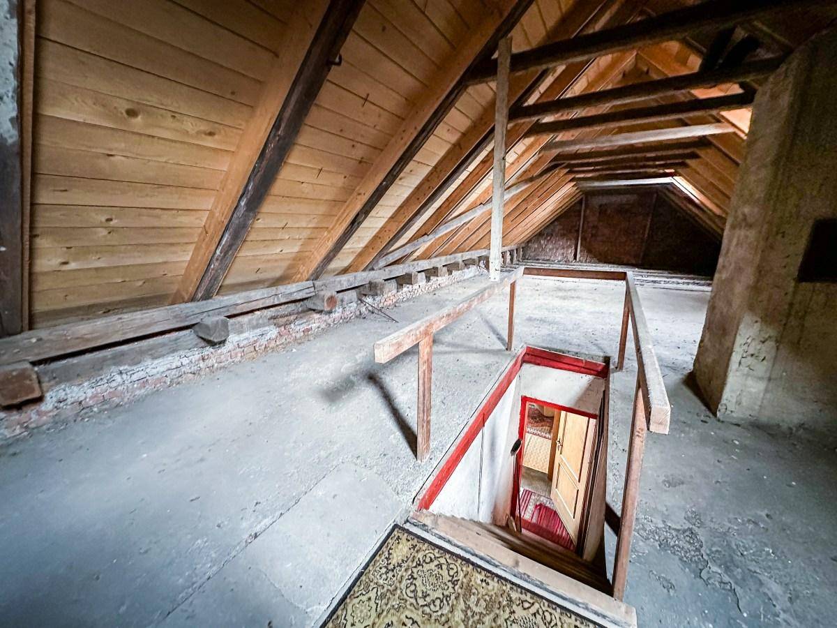 Geräumiger Dachboden mit Holzdachstuhl und Zugang über eine Treppe.