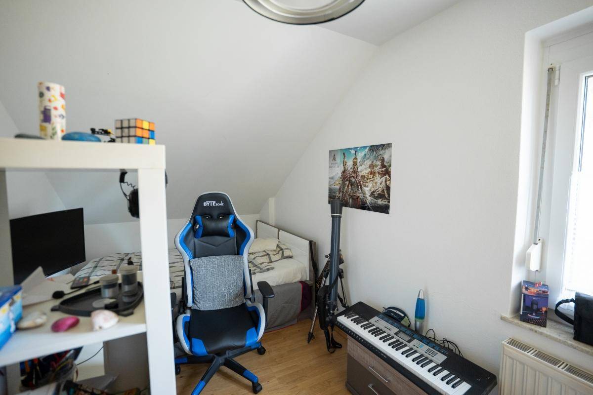 Jugendzimmer im Dachgeschoss mit Bett, Schreibtisch und Dachfenster für natürliches Licht.