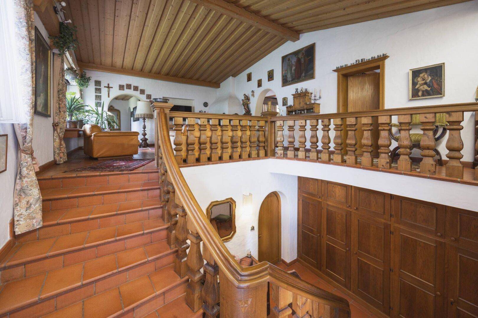 Großzügiger Eingangsbereich mit Holztreppe, Galerie und rustikalen Holzbalken an der Decke.