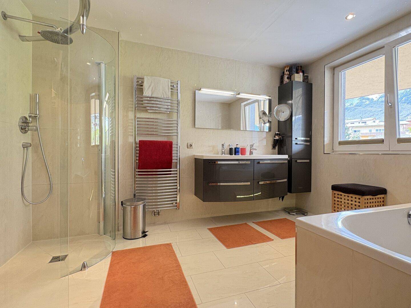 Modernes Badezimmer mit großer Dusche, Badewanne, Doppelwaschbecken und Fenster.