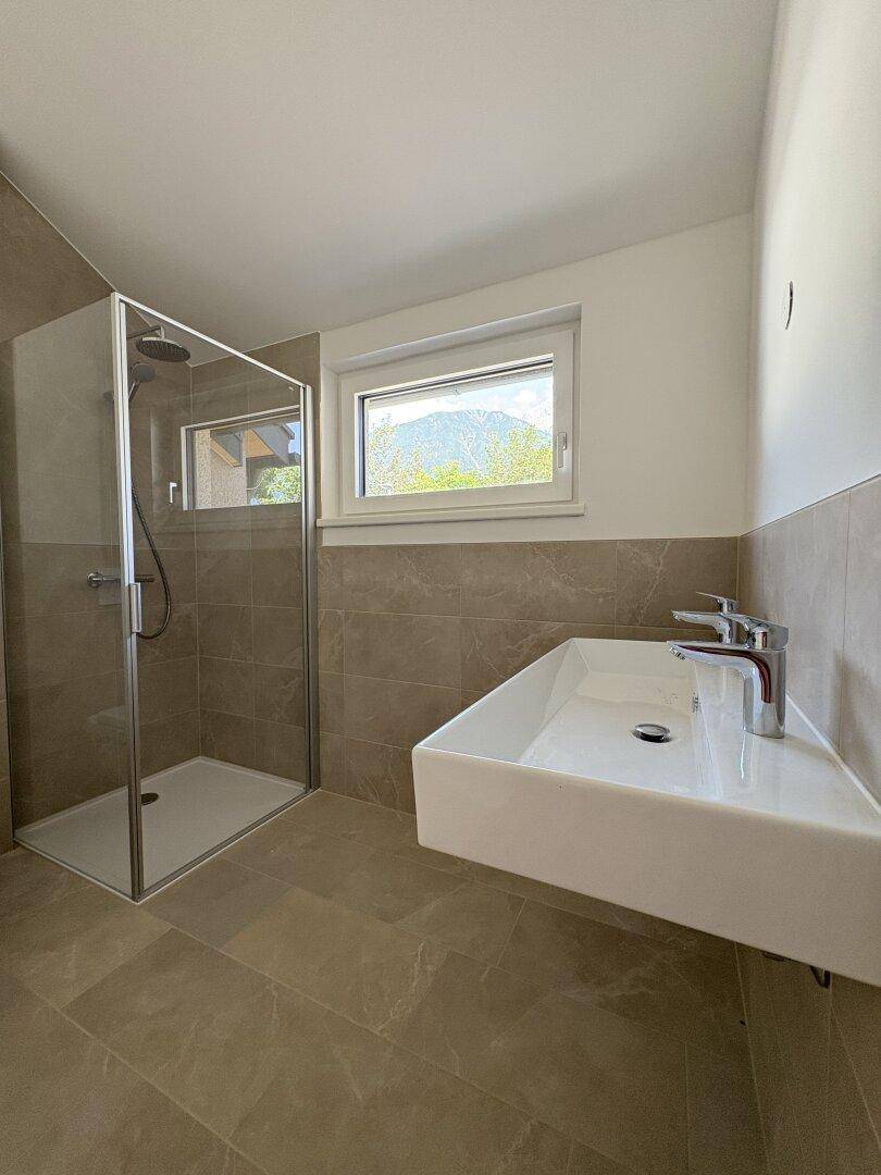 Modernes Badezimmer mit begehbarer Dusche, Einzelwaschbecken und Fenster mit Grünblick.