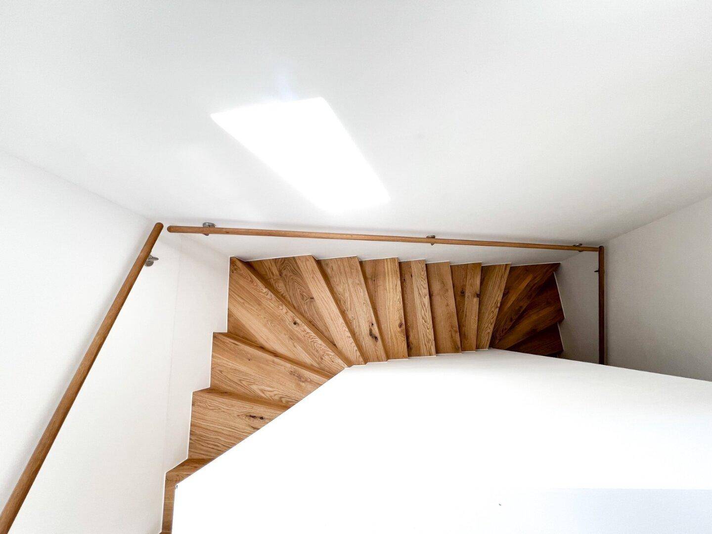 Helle Holztreppe mit elegantem Geländer, die verschiedene Ebenen des Hauses verbindet.
