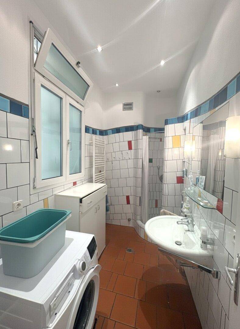 Badezimmer mit farbigen Fliesen, Dusche, Waschbecken und Fenster.