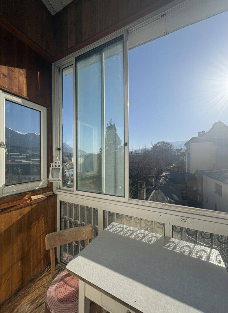 Verglaster Balkon mit Holzwänden, Sitzgelegenheiten und Bergblick.