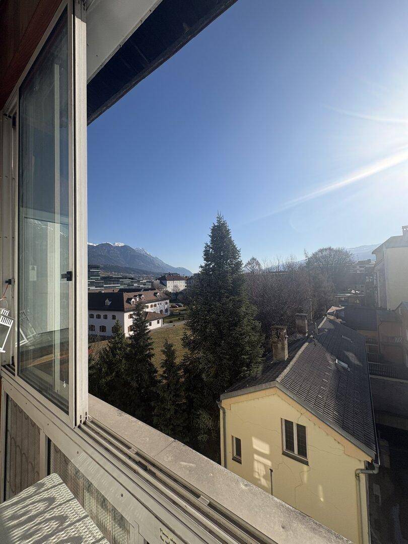 Sonniger Balkon mit weitem Blick auf die Berge und umliegende Häuser.