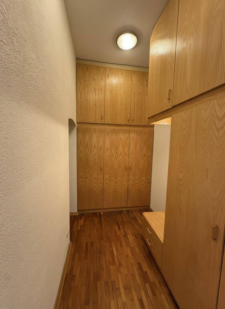 Flur mit Einbauschränken aus Holz und Parkettboden.