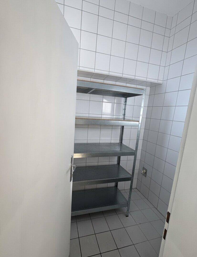Praktischer Abstellraum mit Metallregalen und Fliesenboden für zusätzlichen Stauraum.
