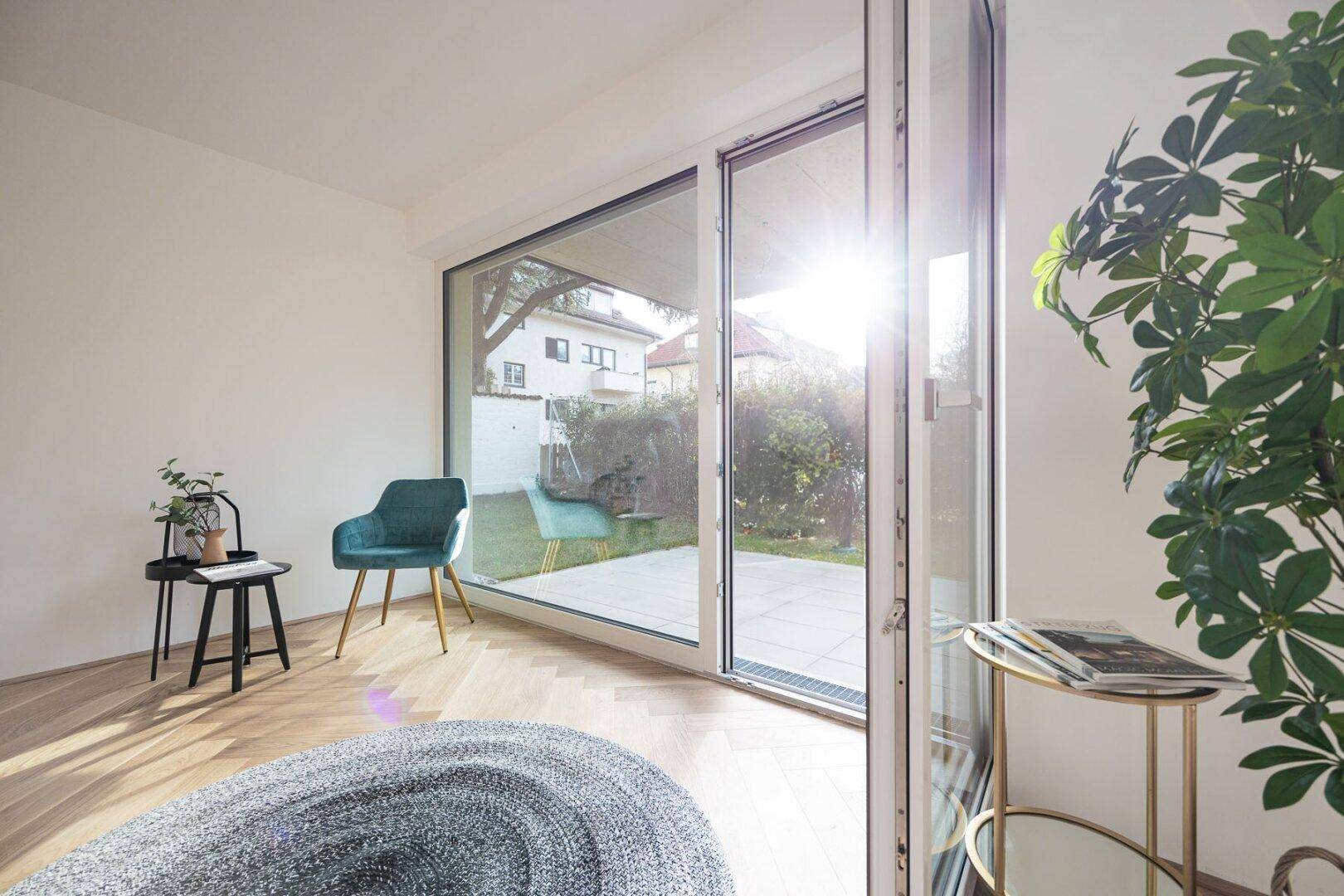Helles Wohnzimmer mit großen Fenstern, Holzboden und direktem Zugang zur sonnigen Terrasse.