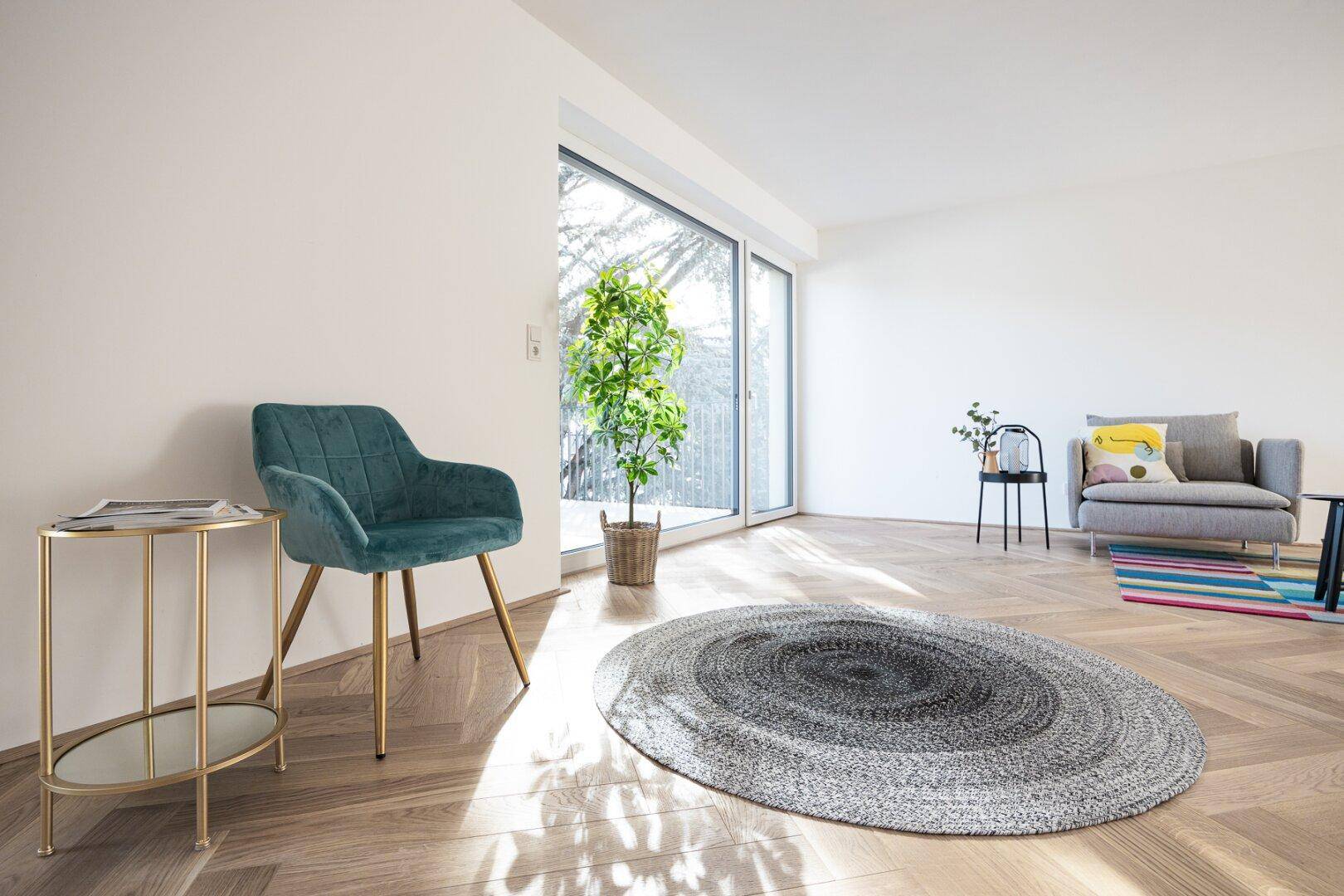 Lichtdurchflutetes Wohnzimmer mit Fischgrätparkett, modernen Möbeln und großen Fenstern.