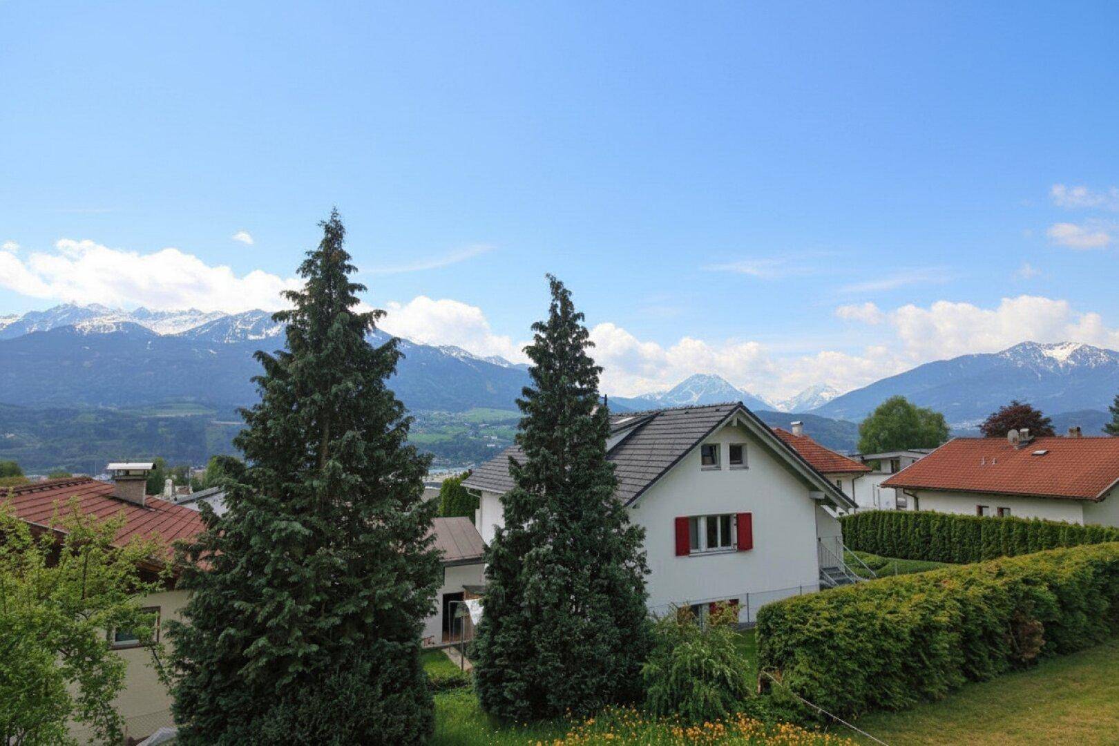 Panoramablick auf die schneebedeckten Berge und die umliegende Wohnsiedlung an einem klaren Tag.