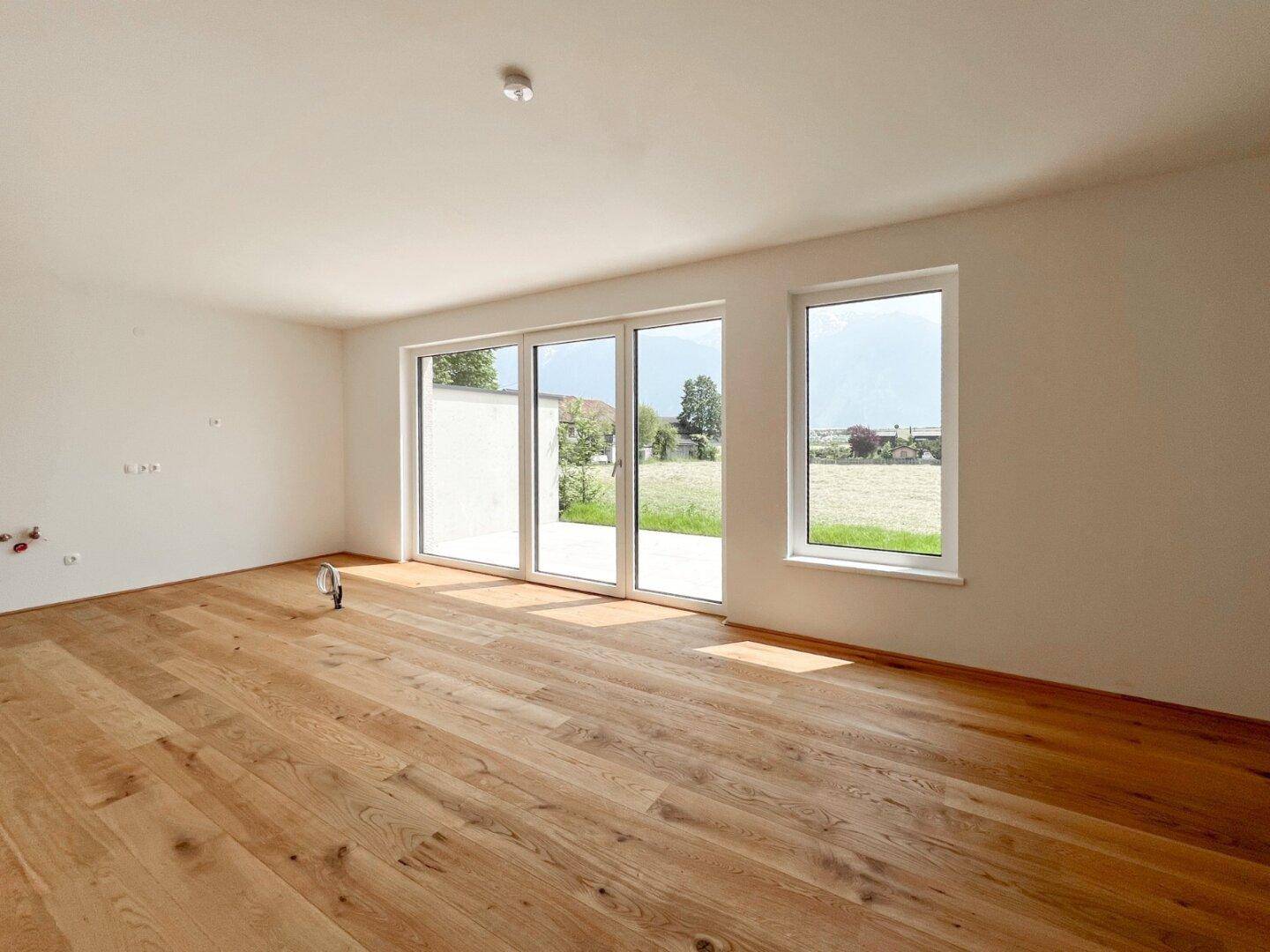 Geräumiges Zimmer mit hellem Holzboden und großen Schiebetüren, die viel Licht hereinlassen.