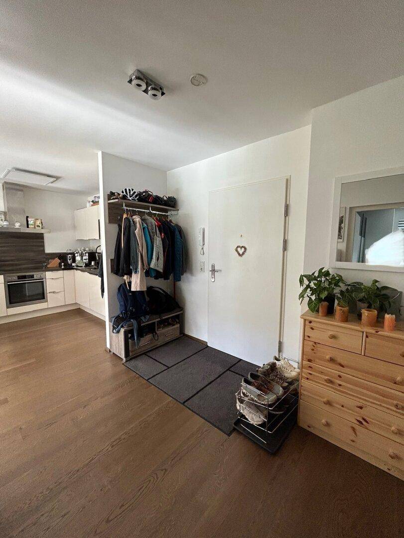Eingangsbereich mit Garderobe, Schuhablage und Blick in die offene Küche.