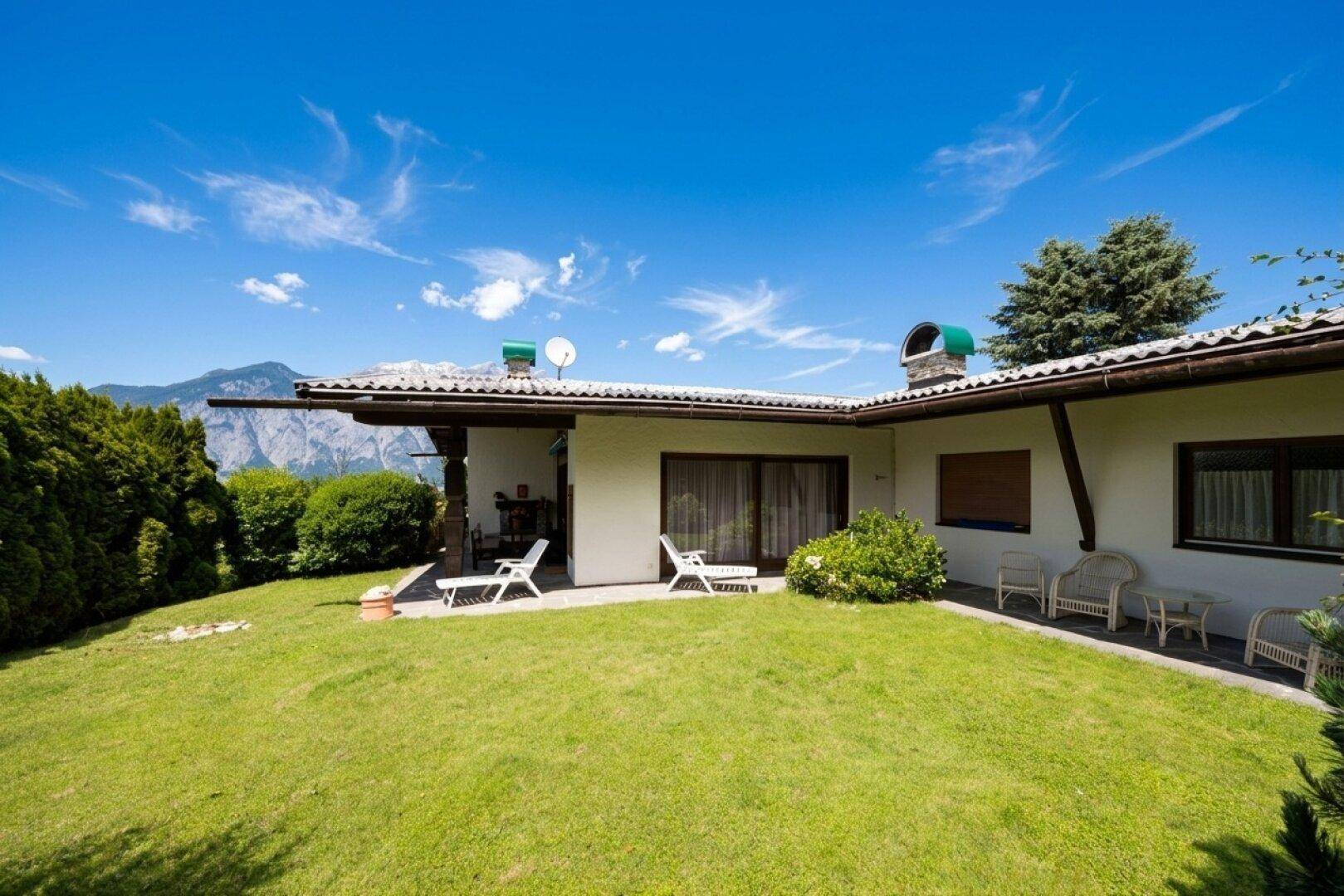 Gepflegter Gartenbereich mit Liegestühlen und Blick auf die umliegenden Berge und Natur.
