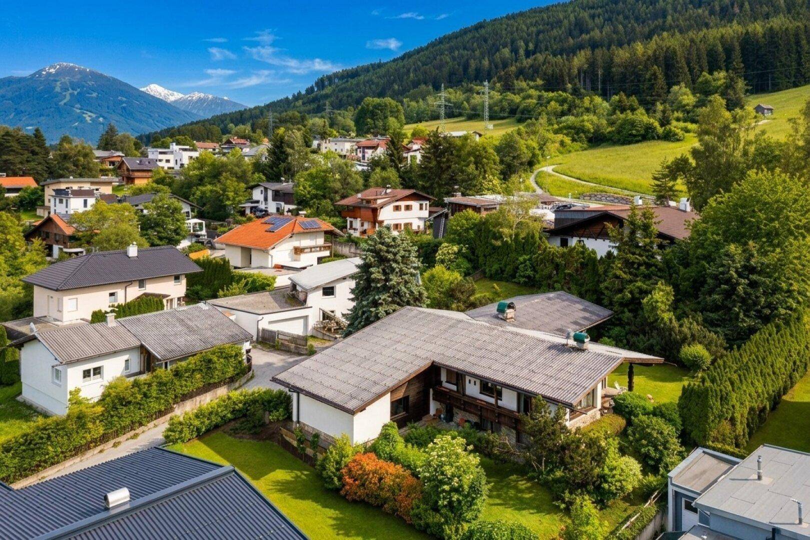 Luftaufnahme des Hauses in einer grünen Wohngegend mit Bergblick und vielen Bäumen.