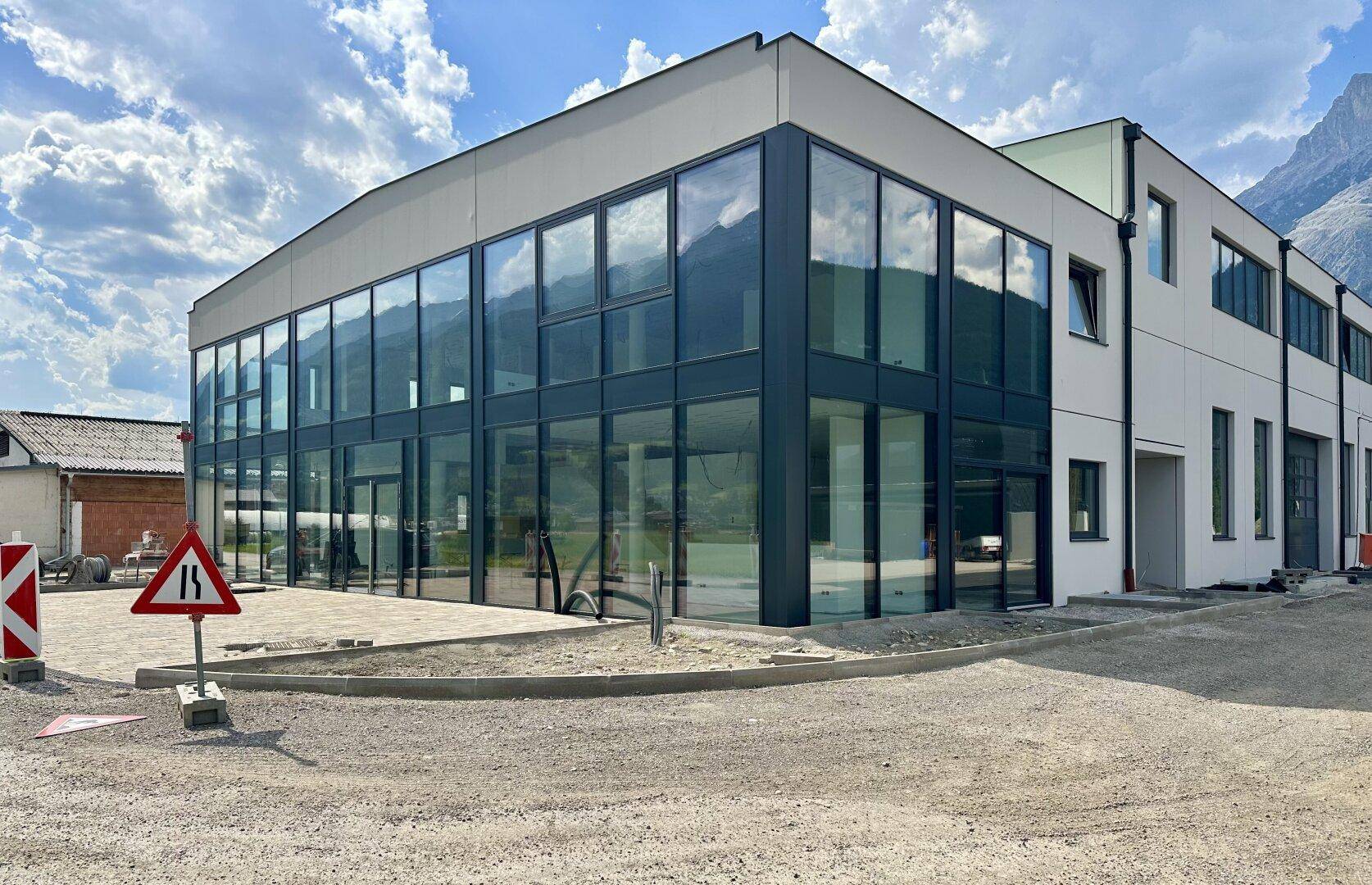 Nahaufnahme der modernen Glasfassade des Geschäftsgebäudes mit Bergkulisse und blauen Himmel.