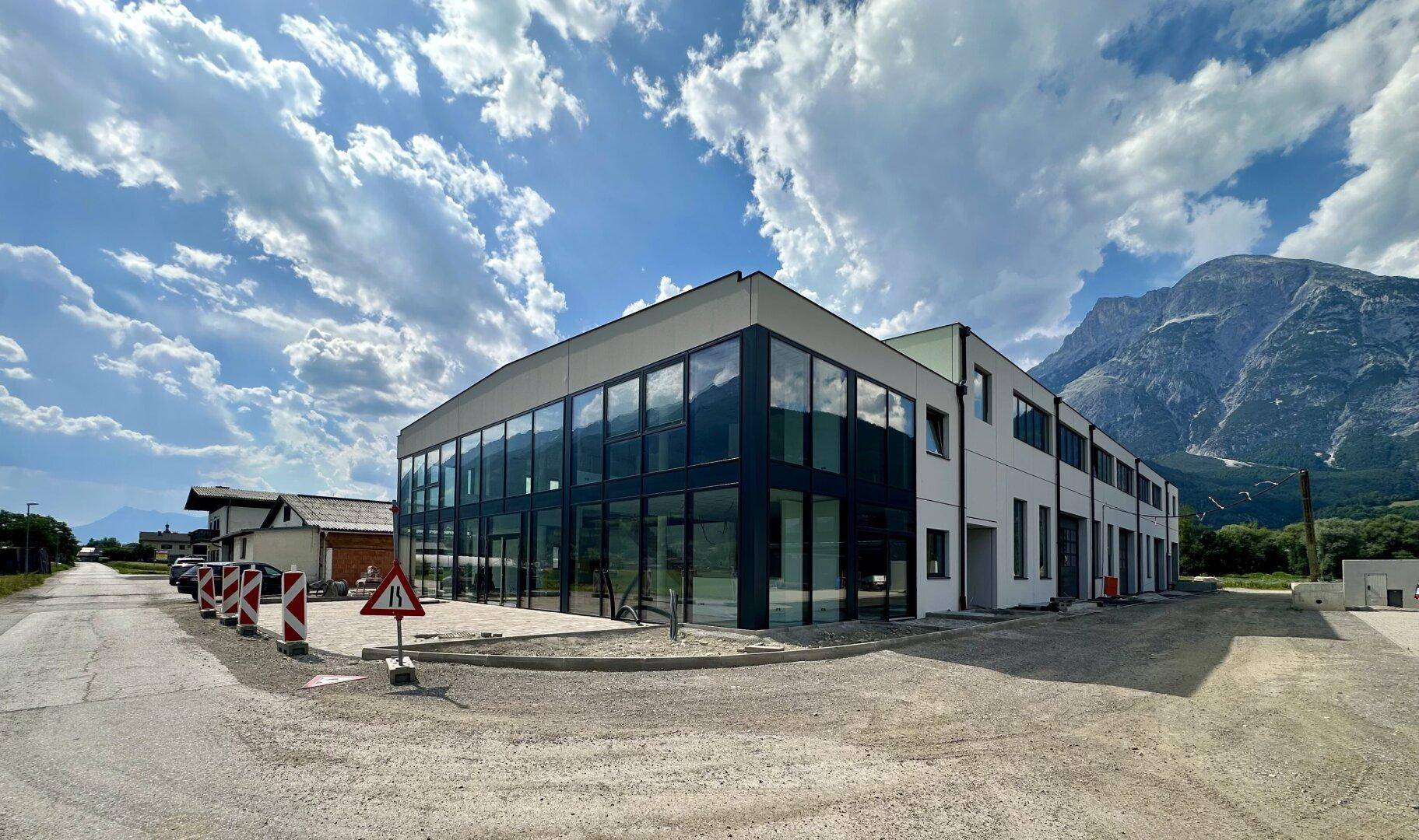 Gesamtansicht des modernen Geschäftsgebäudes mit Glasfassade und Bergpanorama.