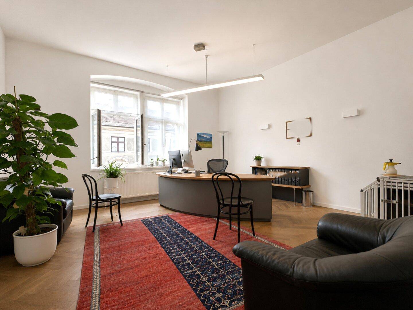 Helles Büro mit geschwungenem Schreibtisch, bequemen Ledersesseln und einem großen Fenster.