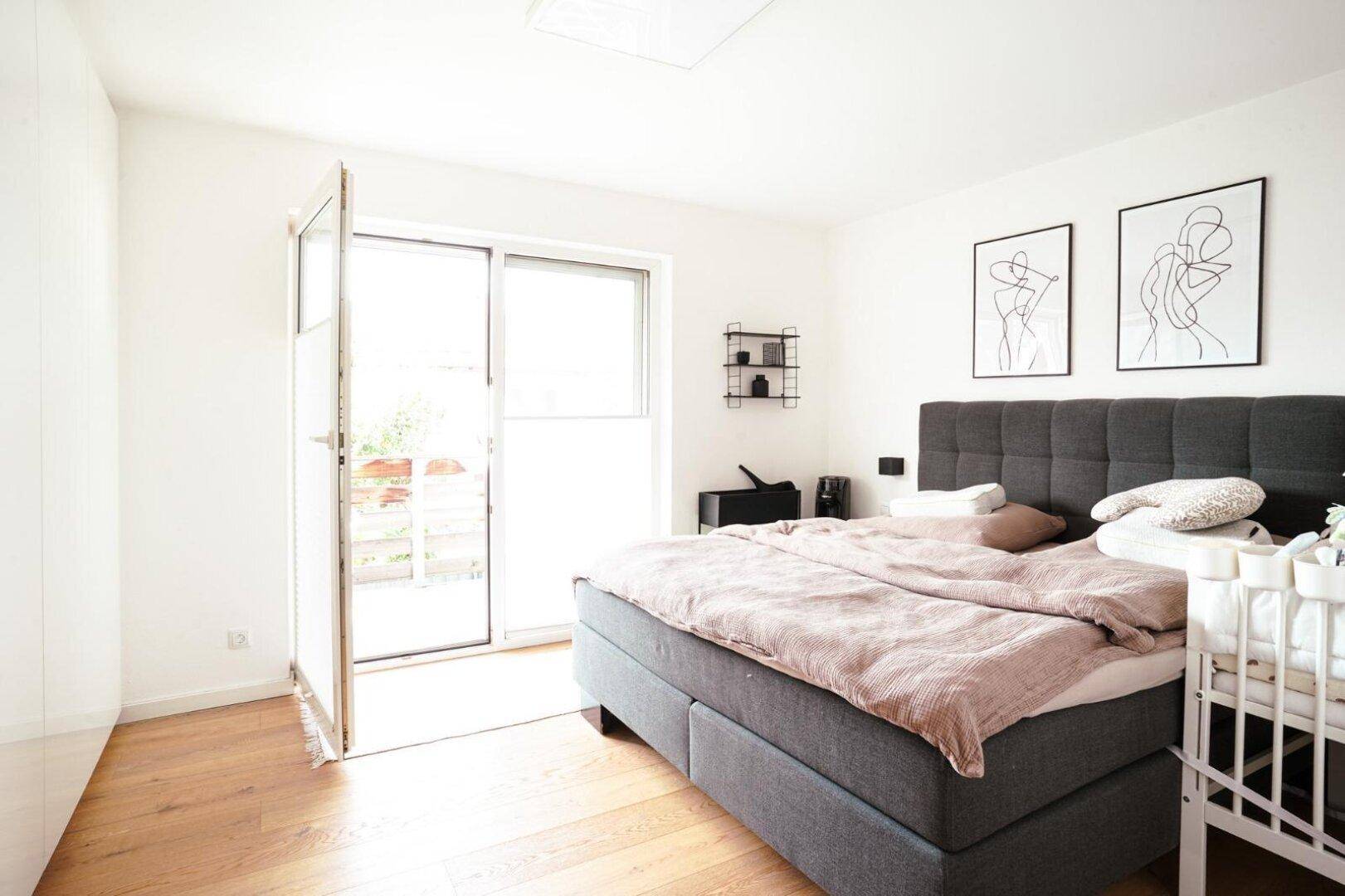 Helles Schlafzimmer mit großem Bett und Holzboden, mit direktem Zugang zu einem Balkon.