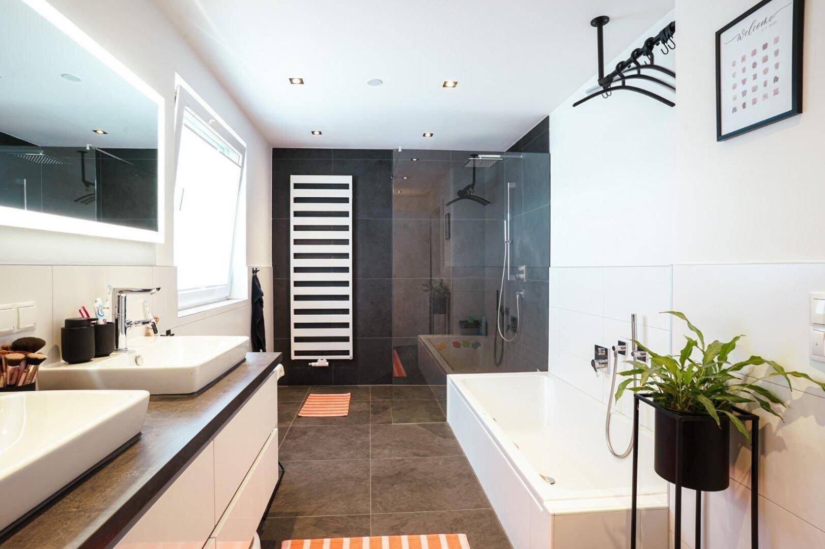 Modernes Badezimmer mit Doppelwaschbecken, Badewanne und begehbarer Dusche, in eleganten Grautönen.