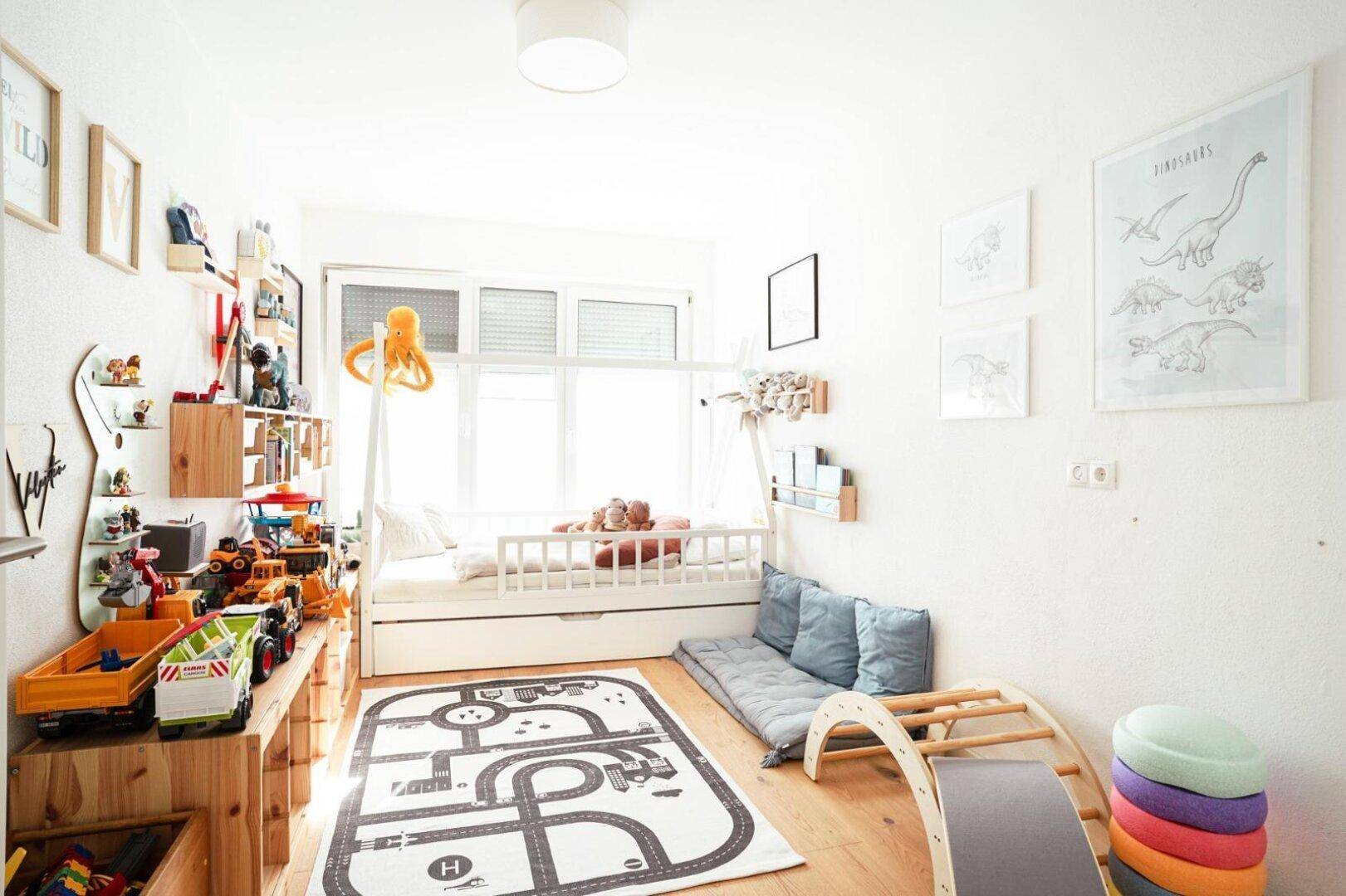 Helles Kinderzimmer mit Spielzeug und einem Bett, ideal für kleine Kinder.