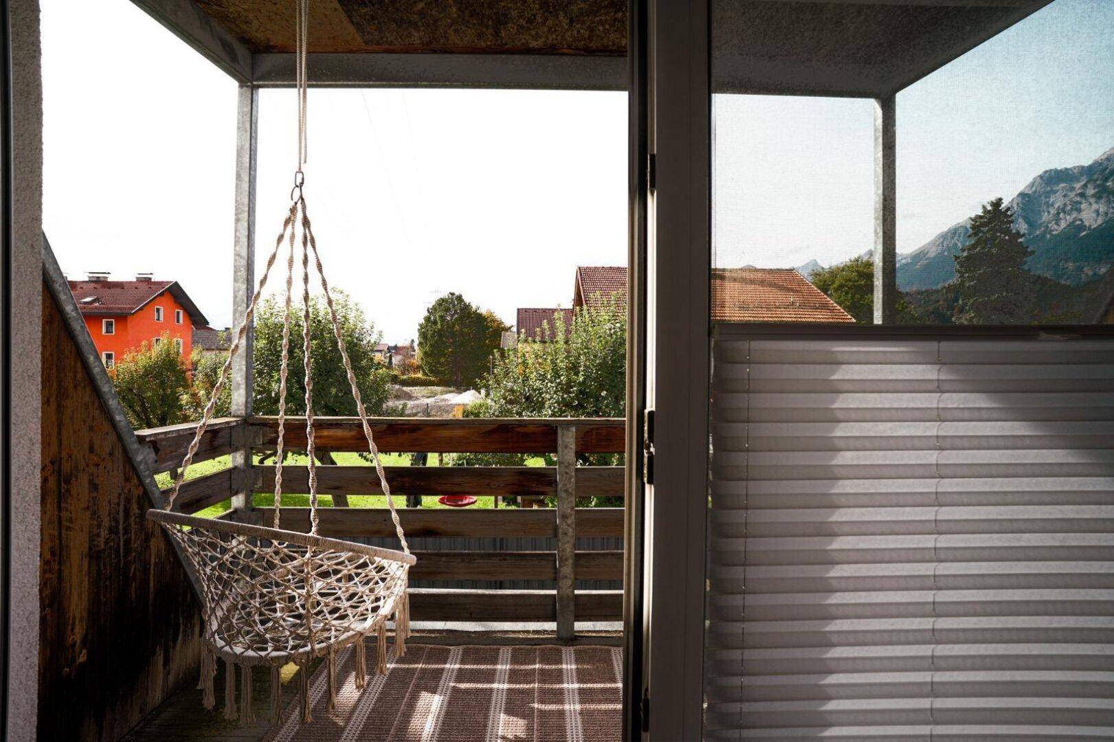 Gemütlicher Balkon mit Hängesessel und weitem Blick auf die umliegende Landschaft und Berge.