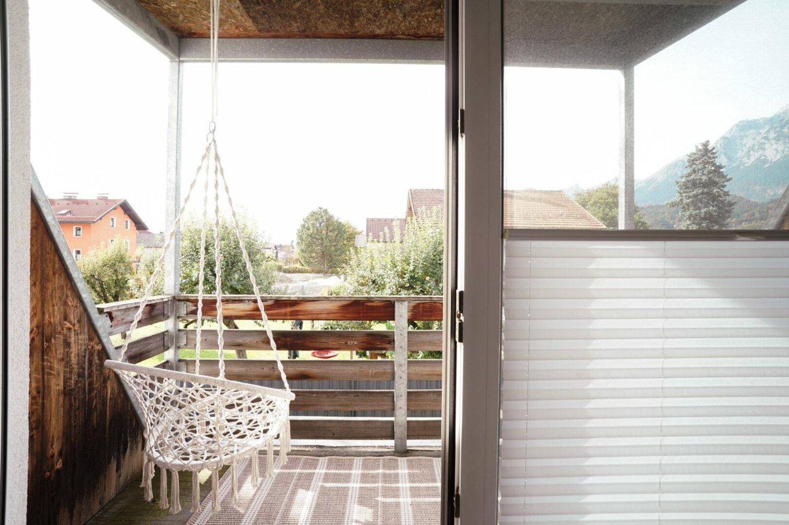 Gemütlicher Balkon mit Hängesessel und weitem Blick auf die umliegende Landschaft und Berge.