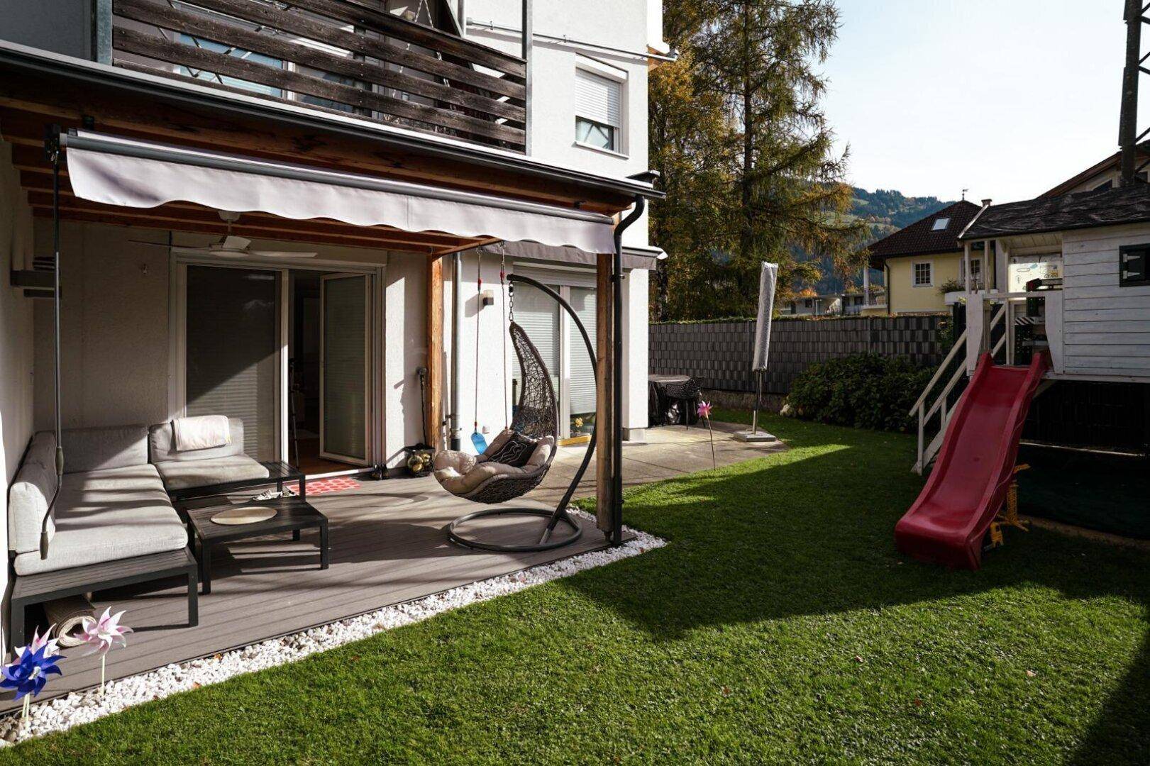 Großer Gartenbereich mit Terrasse, Spielrutsche und Sitzgelegenheiten, ideal für Familien.