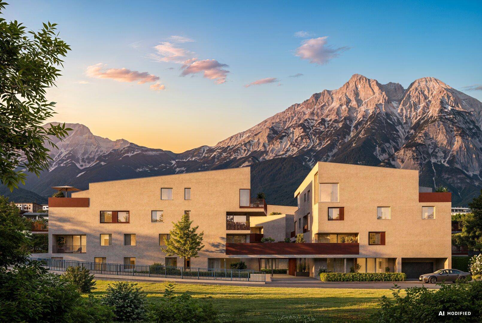 Moderne Wohnanlage mit alpiner Architektur und Bergblick bei Sonnenuntergang.