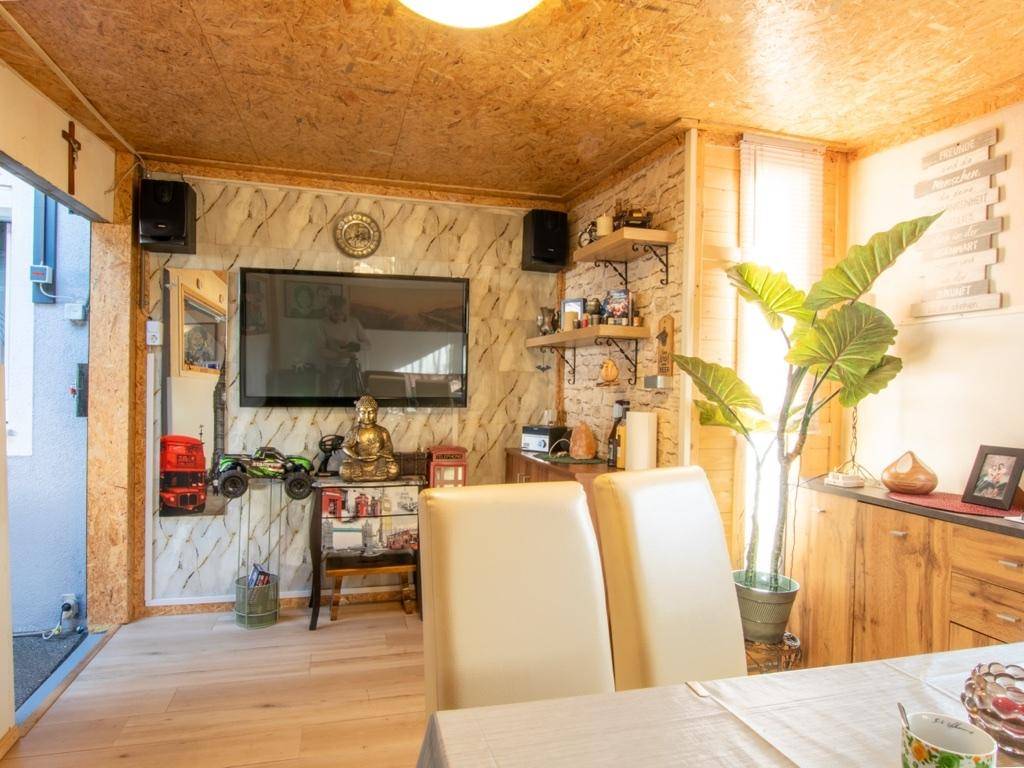 Gemütlicher Raum mit Holzverkleidung, Fernseher und dekorativen Elementen.