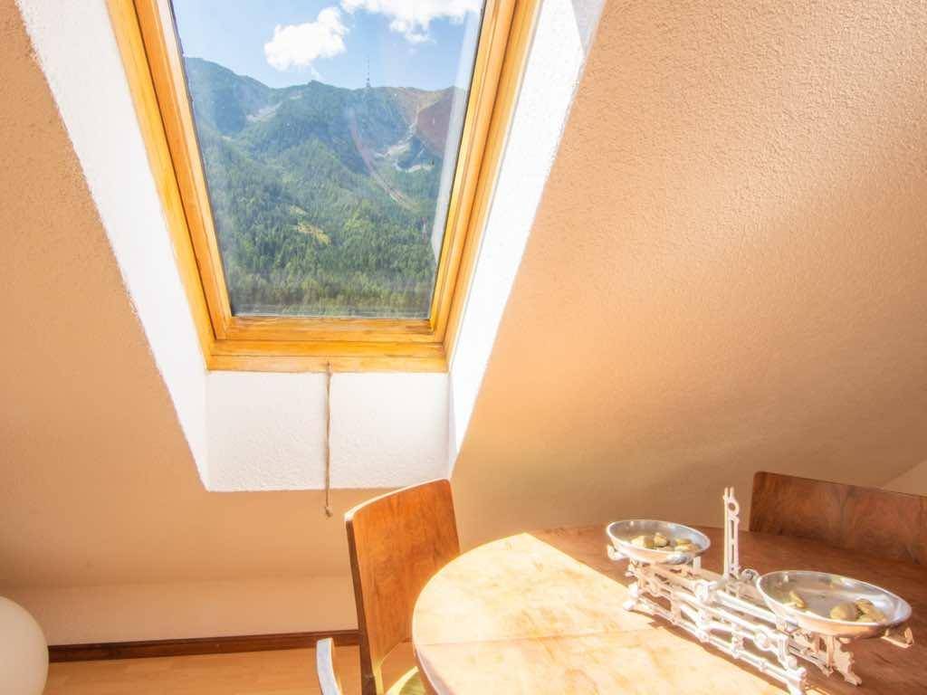 Essbereich mit Holztisch und einem Dachfenster, das einen atemberaubenden Bergblick bietet.