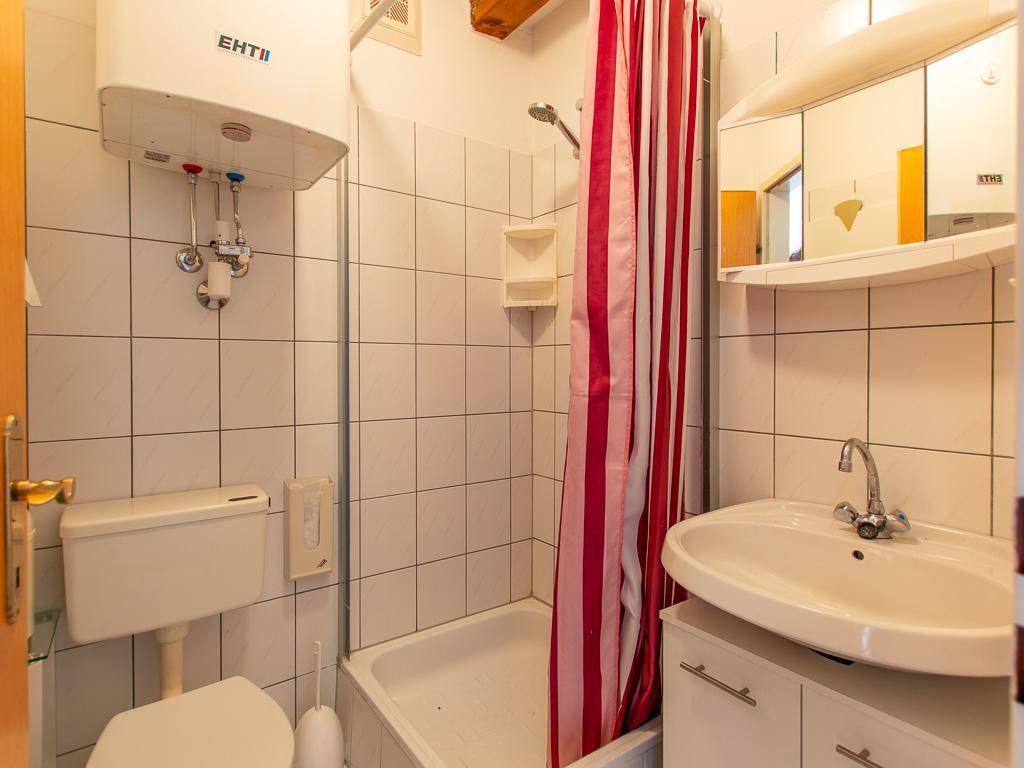 Kompaktes Badezimmer mit Dusche, WC, Waschbecken und weiß gefliesten Wänden in Standardausführung.