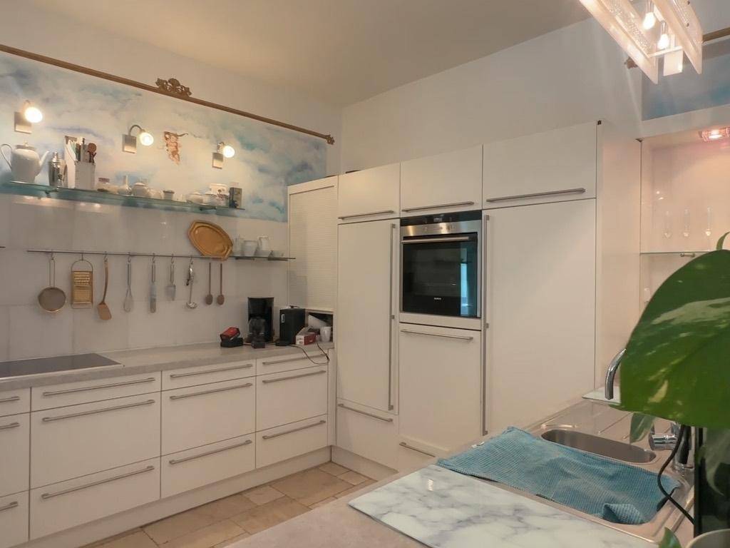 Moderne weiße Einbauküche mit integrierten Geräten und Marmor-Arbeitsplatte.