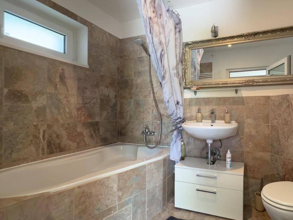 Badezimmer mit Badewanne, Duschvorhang, Waschbecken und Fenster.