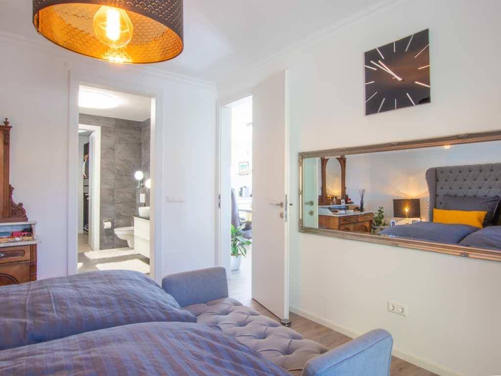 Gemütliches Schlafzimmer mit großem Bett, Holzboden und direktem Zugang zu einem modernen Badezimmer.