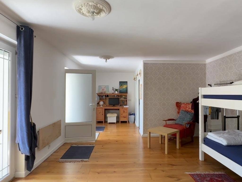 Geräumiges Zimmer mit Holzboden, Etagenbett und Schreibtischbereich.
