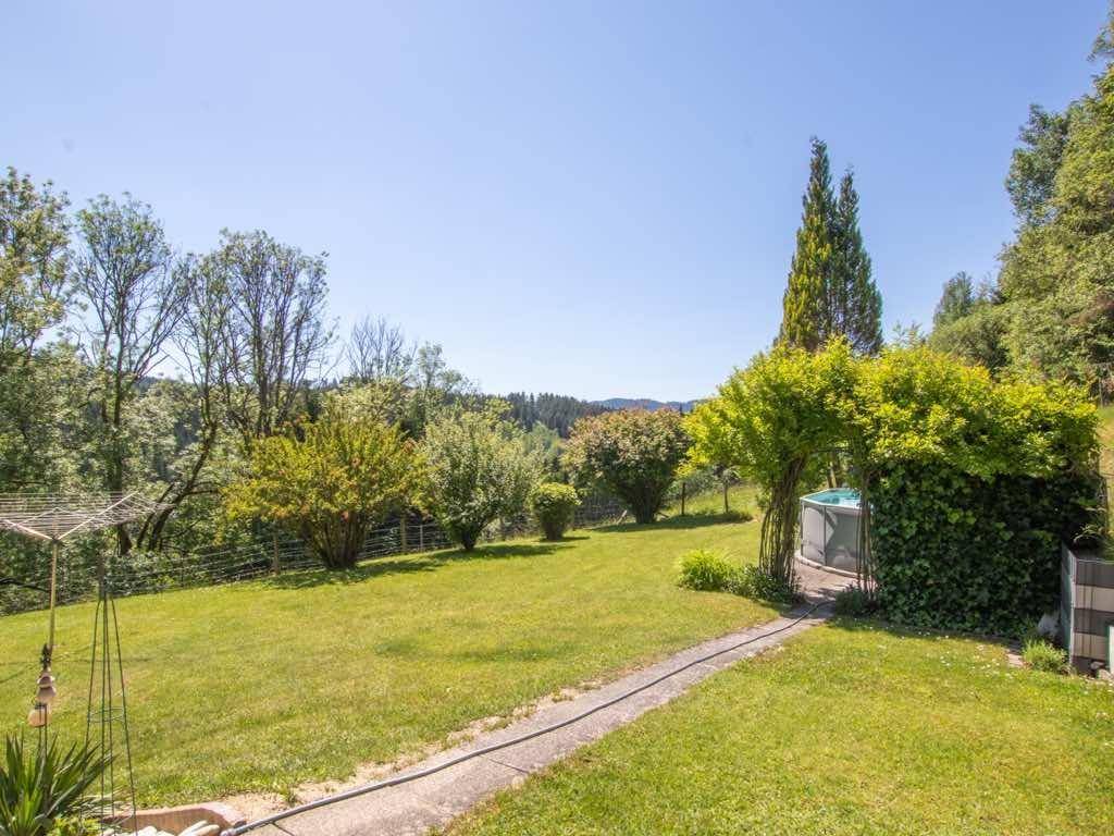 Großer, gepflegter Garten mit Rasenfläche, Sträuchern und einem kleinen Whirlpool im Freien.